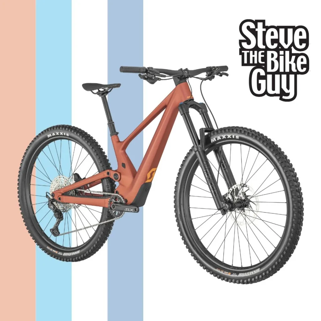 Orange-ish Scott mountain bike on background showing STBG race flag and logo.