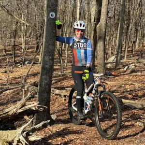 Kristin sitting on her Scott Genius, leaning on a tree in Ashland Town forest.