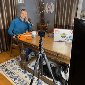 Steve sitting in front of video setup with Daisy under thet able.