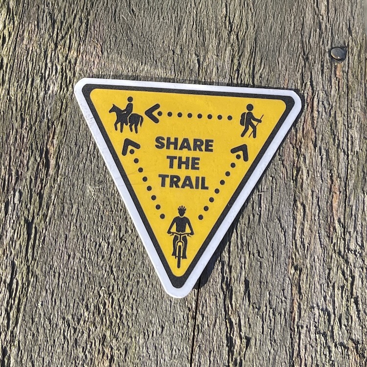 Sticker showing the Share the Trail triangle