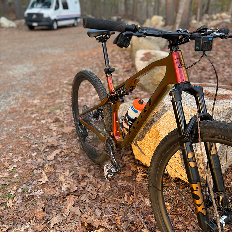 Allied mountain biking leaning on a boulder.